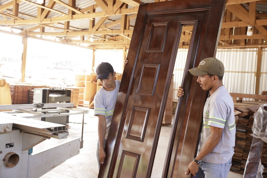 Carpinteros trasladando una puerta de madera en su taller